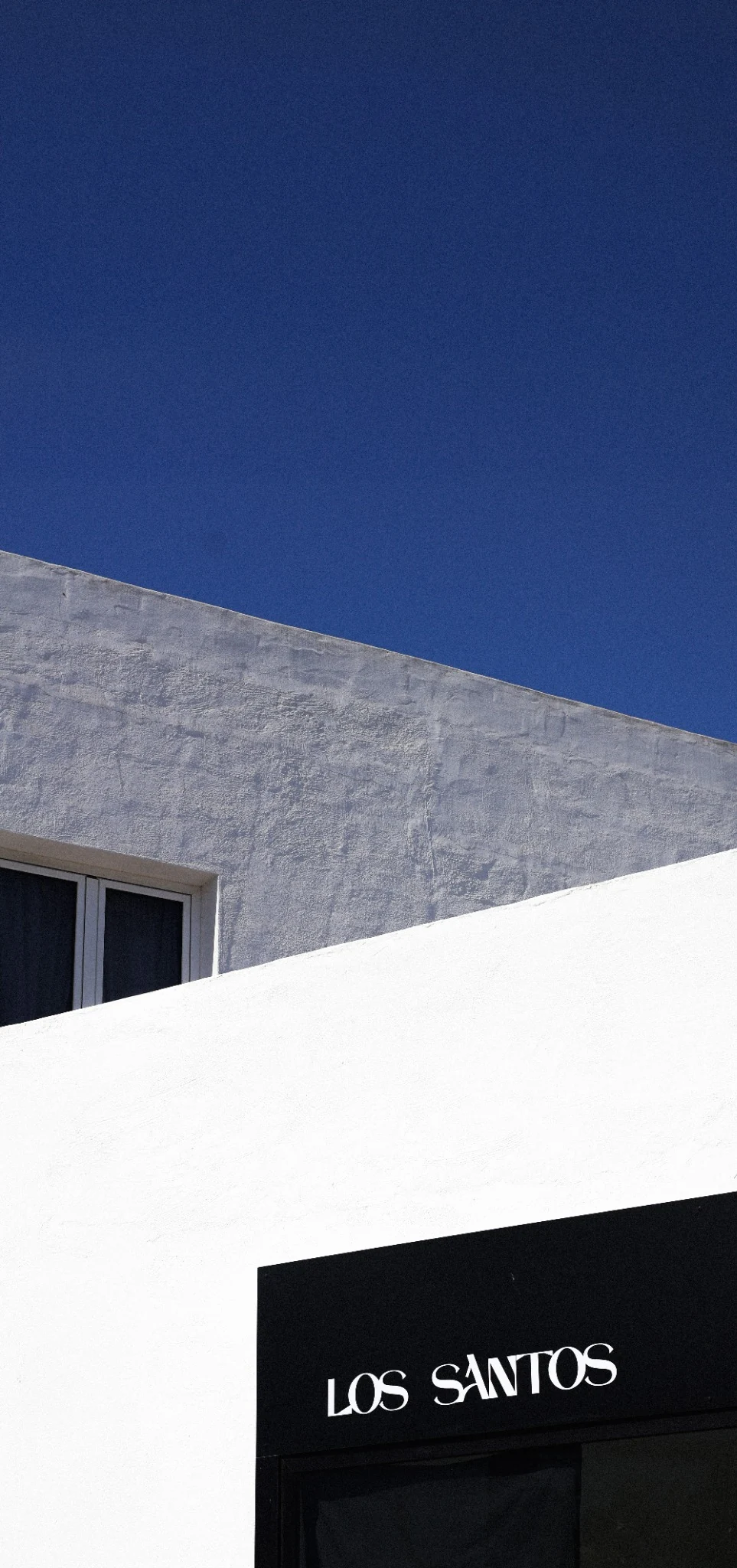 Close vertical view of white and grey architecture against a blue Lanzarote sky.